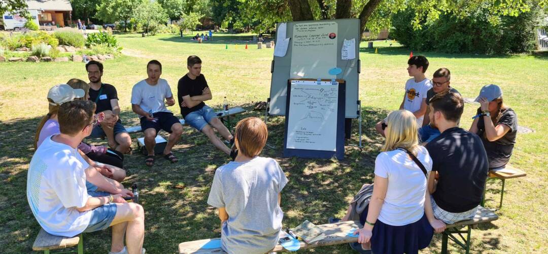 Gruppe diskutiert im Freien auf Wiese