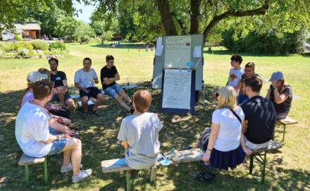 Gruppe diskutiert im Freien auf Wiese