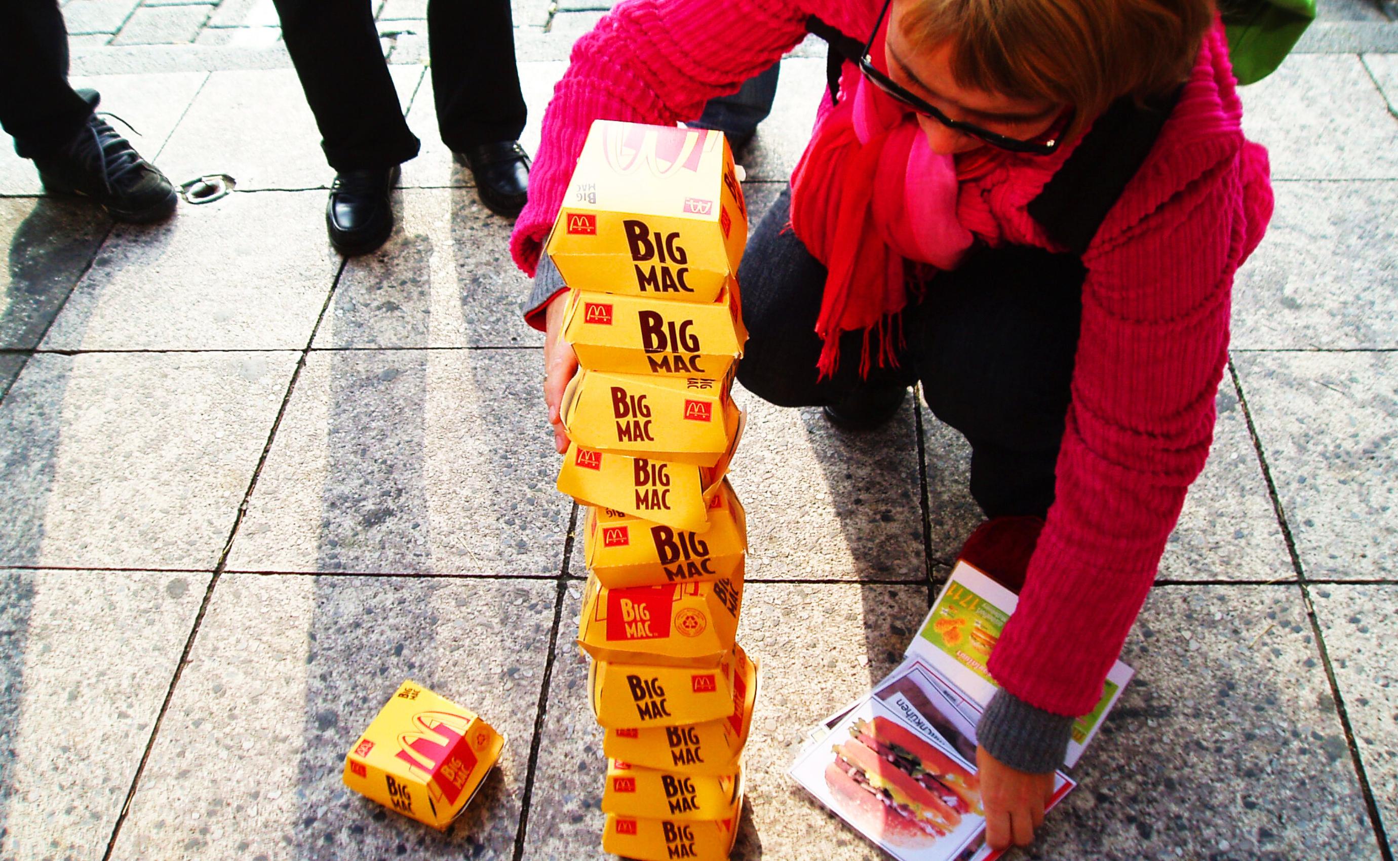 Frau stapelt Big Mac Kartons auf Gehweg.