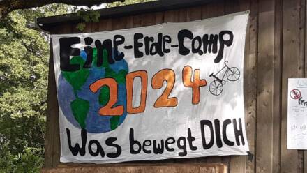 Eine-Erde-Camp 2024 Banner mit Weltkarte und Fahrrad - Was bewegt dich.