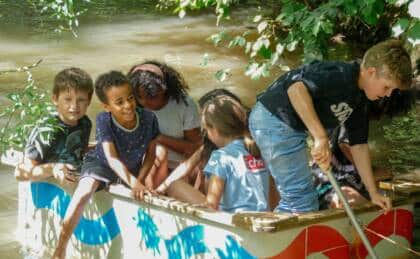 Kinder spielen auf einem Boot im Wasser.