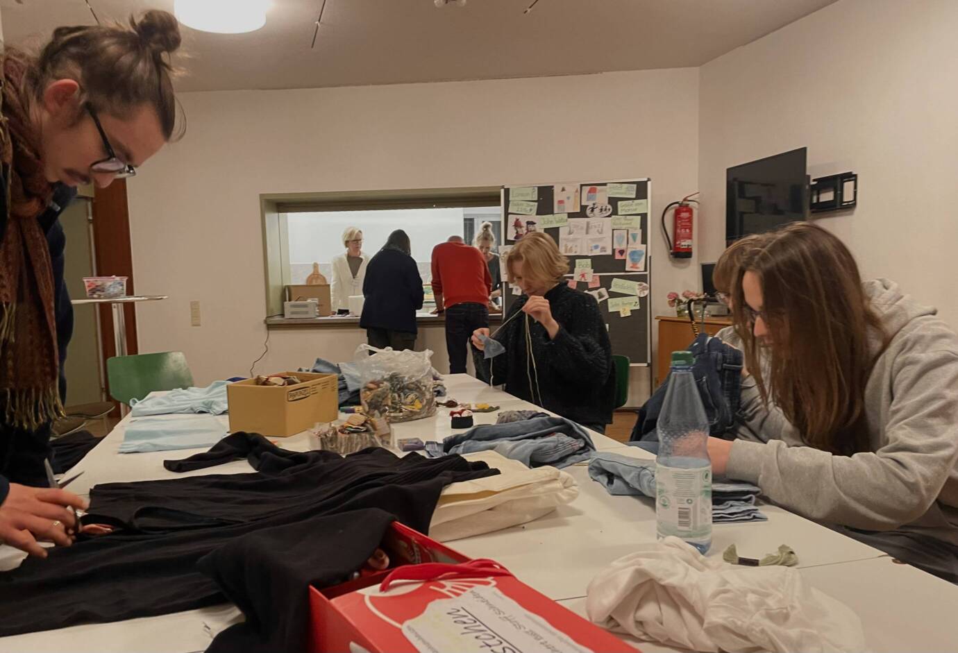 Personen arbeiten an einem Tisch mit Stoffen.