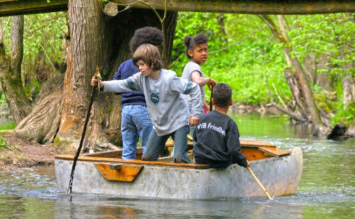 Kinder in einem Boot auf einem Fluss im Wald.