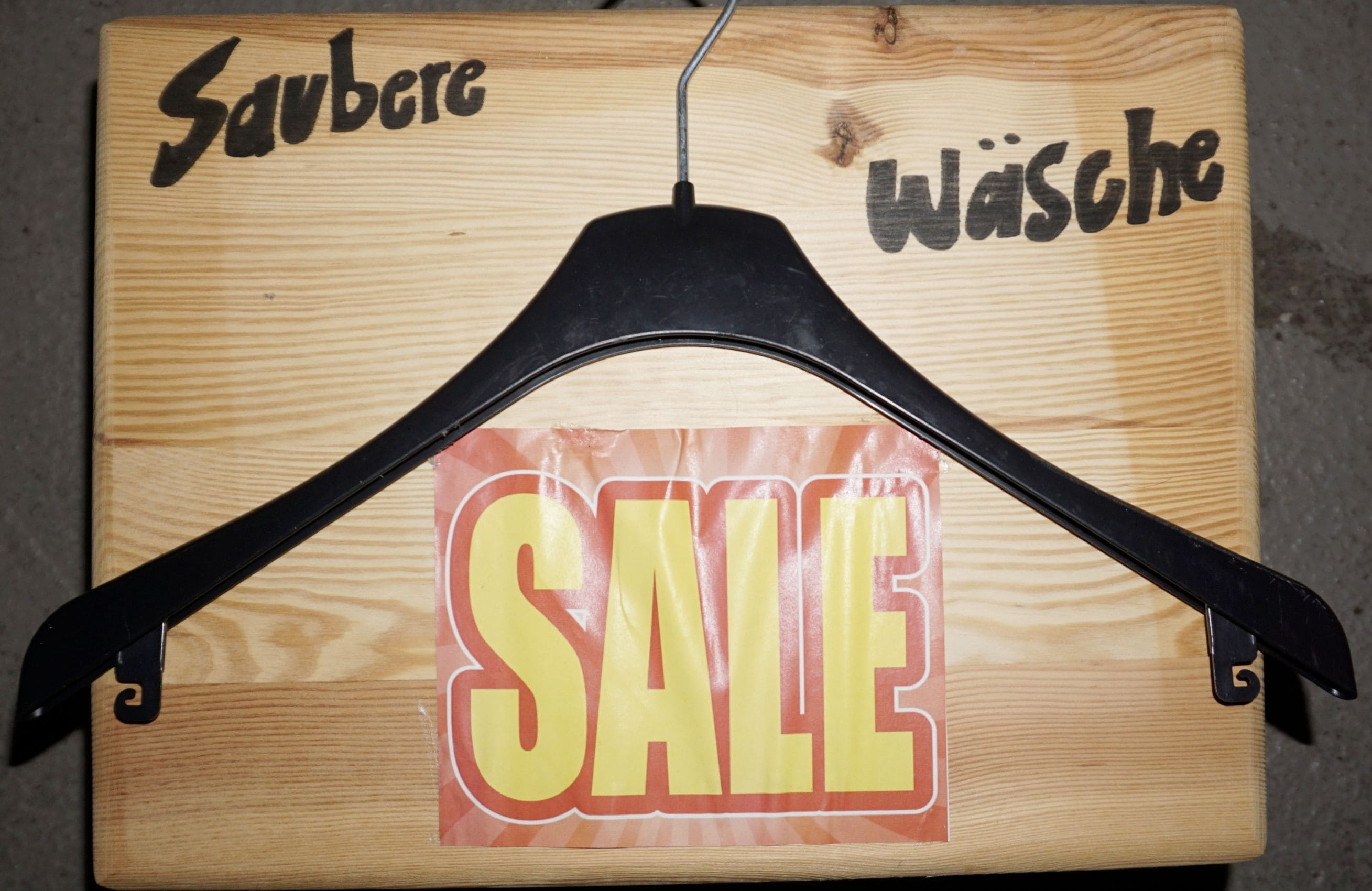 Kleiderbügel mit Sale-Schild auf Holzbank