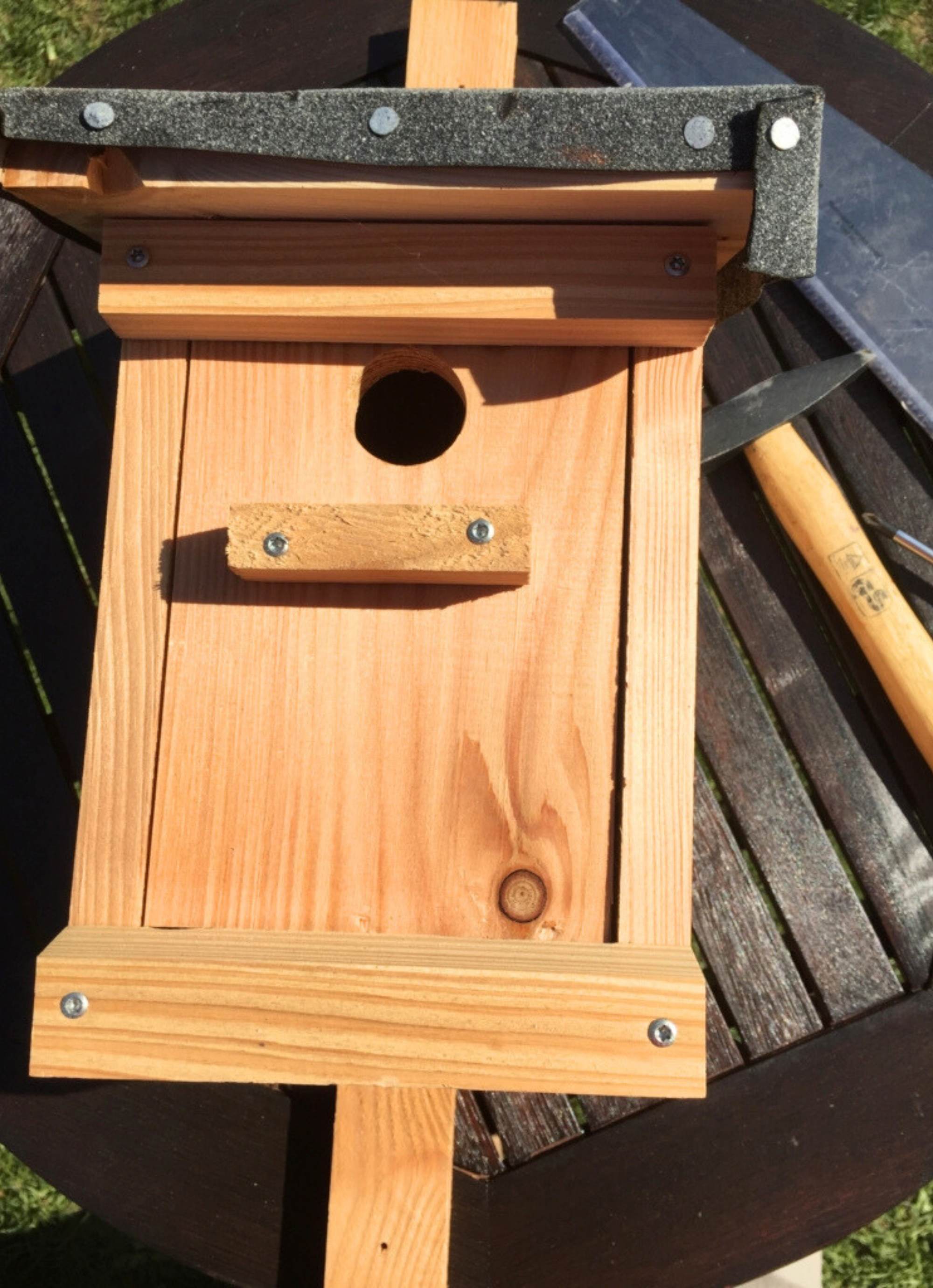 Holznistkasten mit Einflugloch auf Tisch.