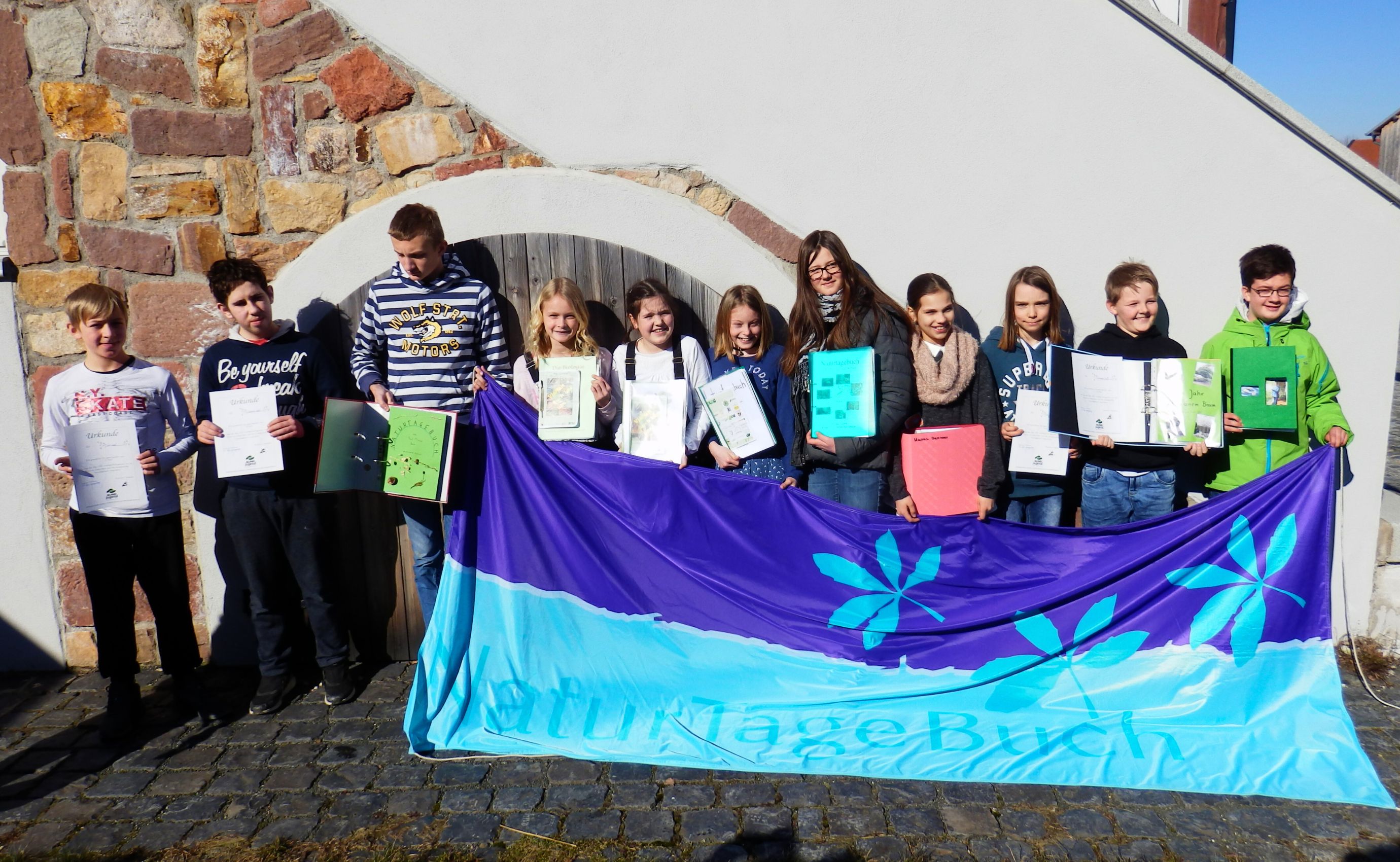 Gruppe von Kindern mit Urkunden und Naturtagebuch.