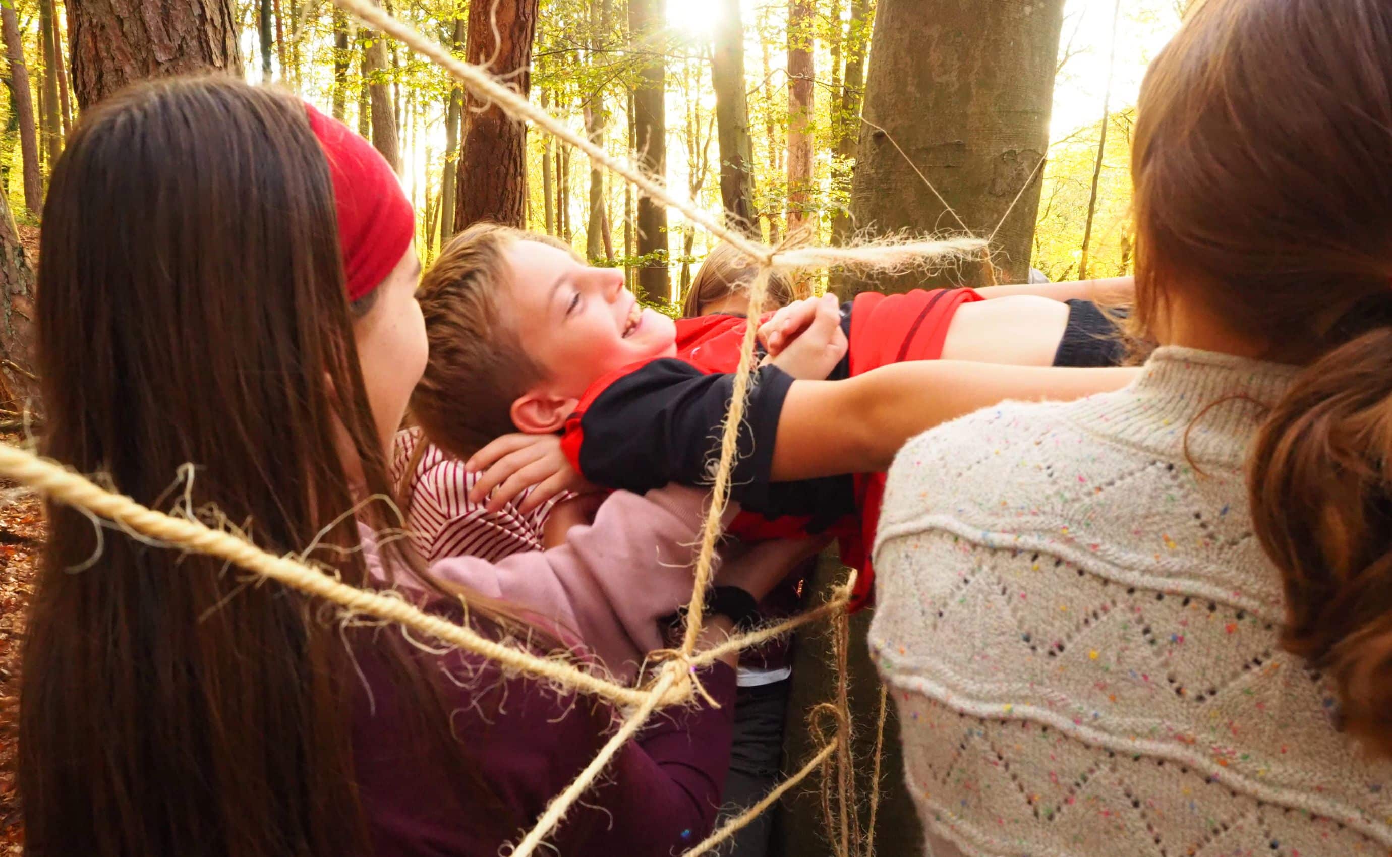 Kinder spielen im Wald mit Seilen