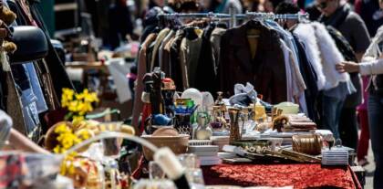 Großer Flohmarkt mit Kleidung und Geschirr.