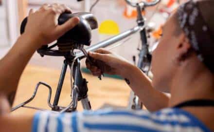 Frau repariert den Sattel an einem Fahrrad.