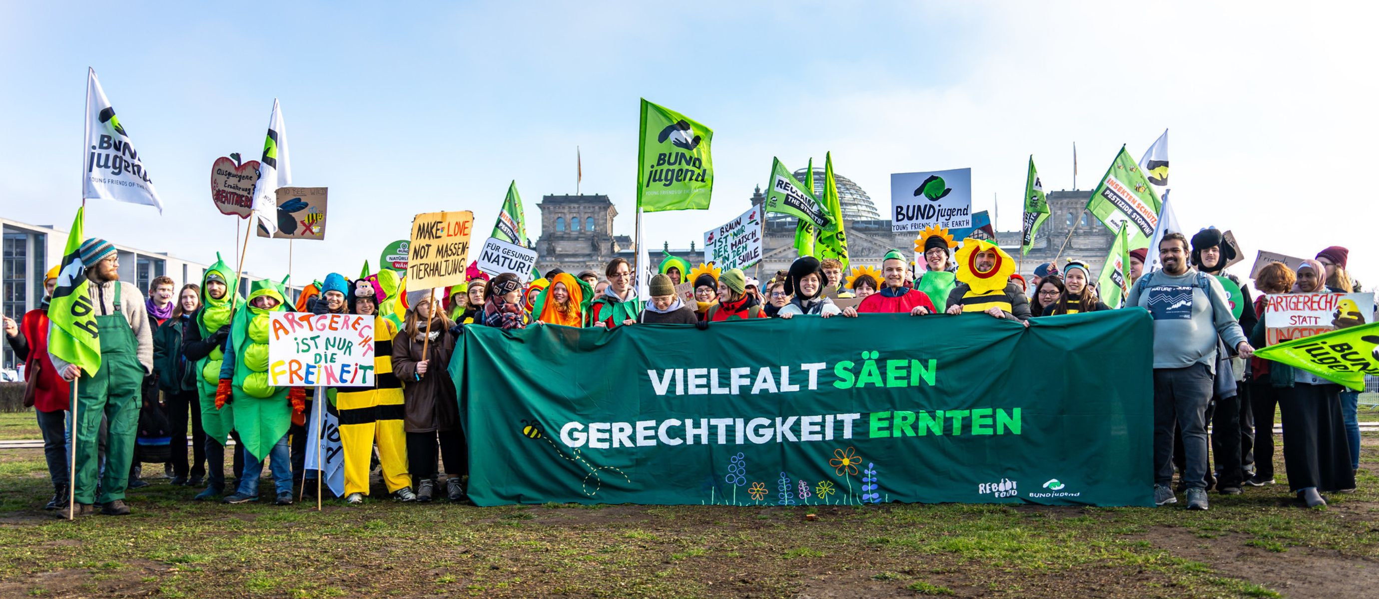 Menschen demonstrieren vor dem Reichstagsgebäude mit Bannern.