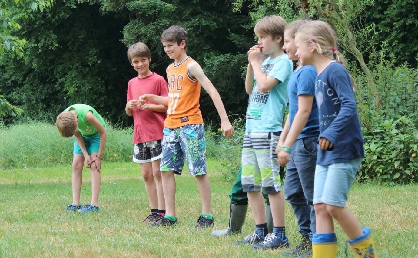 Kinder spielen als Gruppe auf einer Wiese.