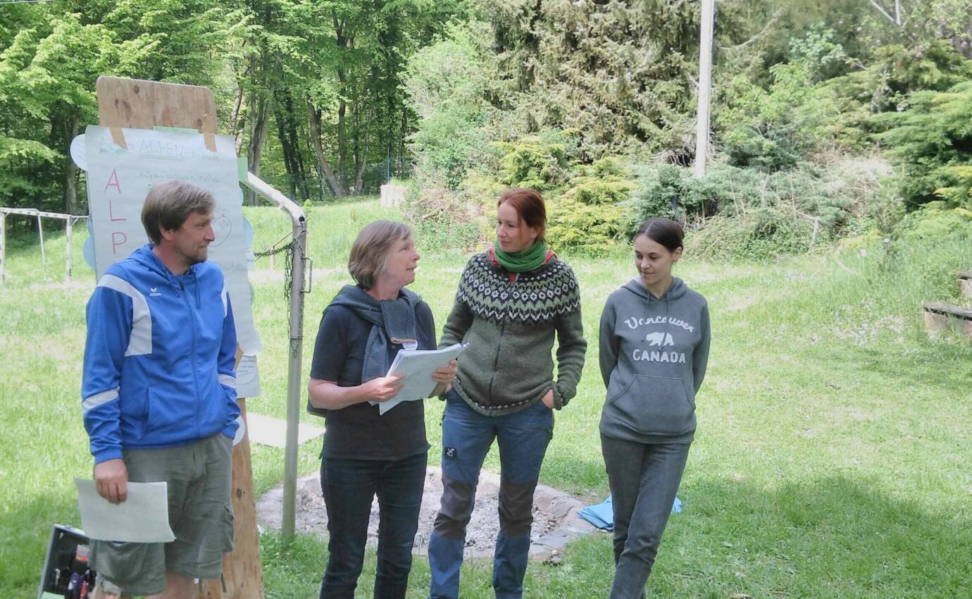 vier Personen stehen im freien und halten einen Vortrag