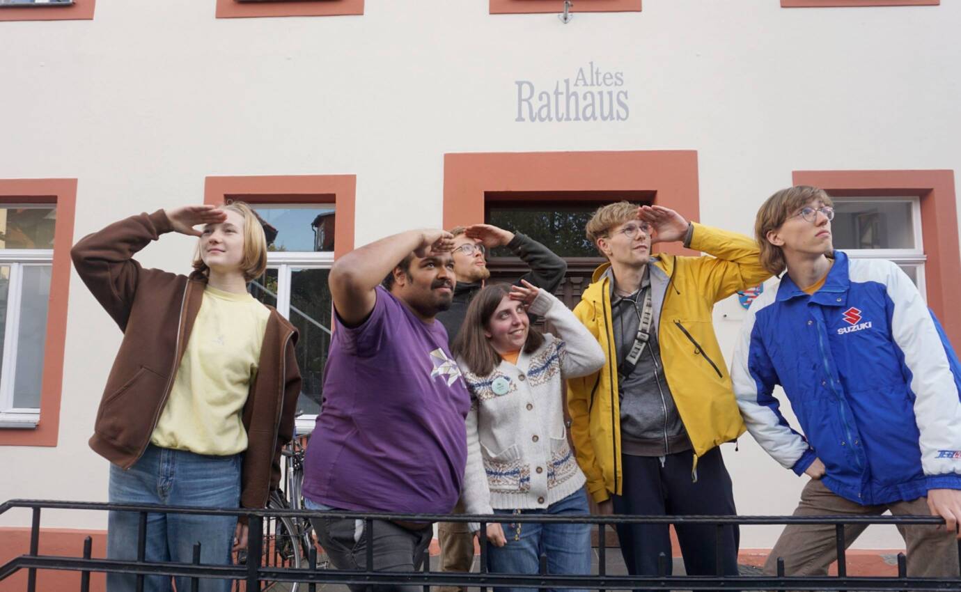 Personengruppe vor dem Alten Rathaus blickt in die Ferne.
