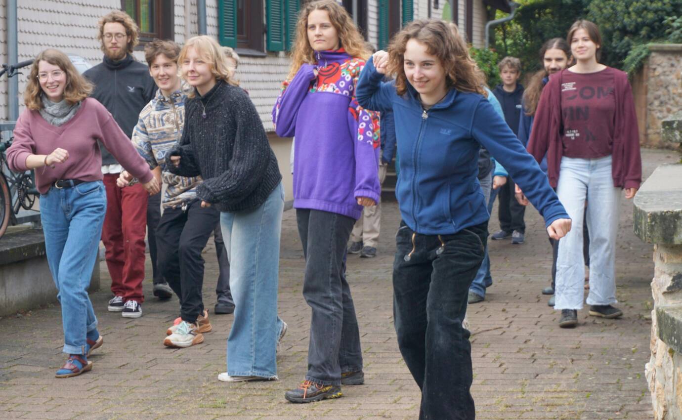 Gruppe von Menschen steht lächelnd draußen, vor einem Gebäude.