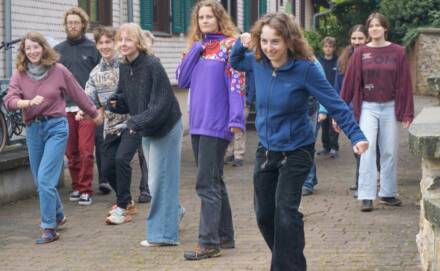 Gruppe von Menschen steht lächelnd draußen, vor einem Gebäude.