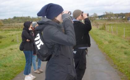 Menschen beobachten mit Ferngläsern in der Natur.