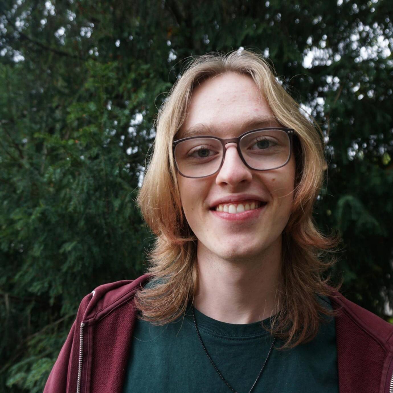 Lächelnde Person vor Bäumen