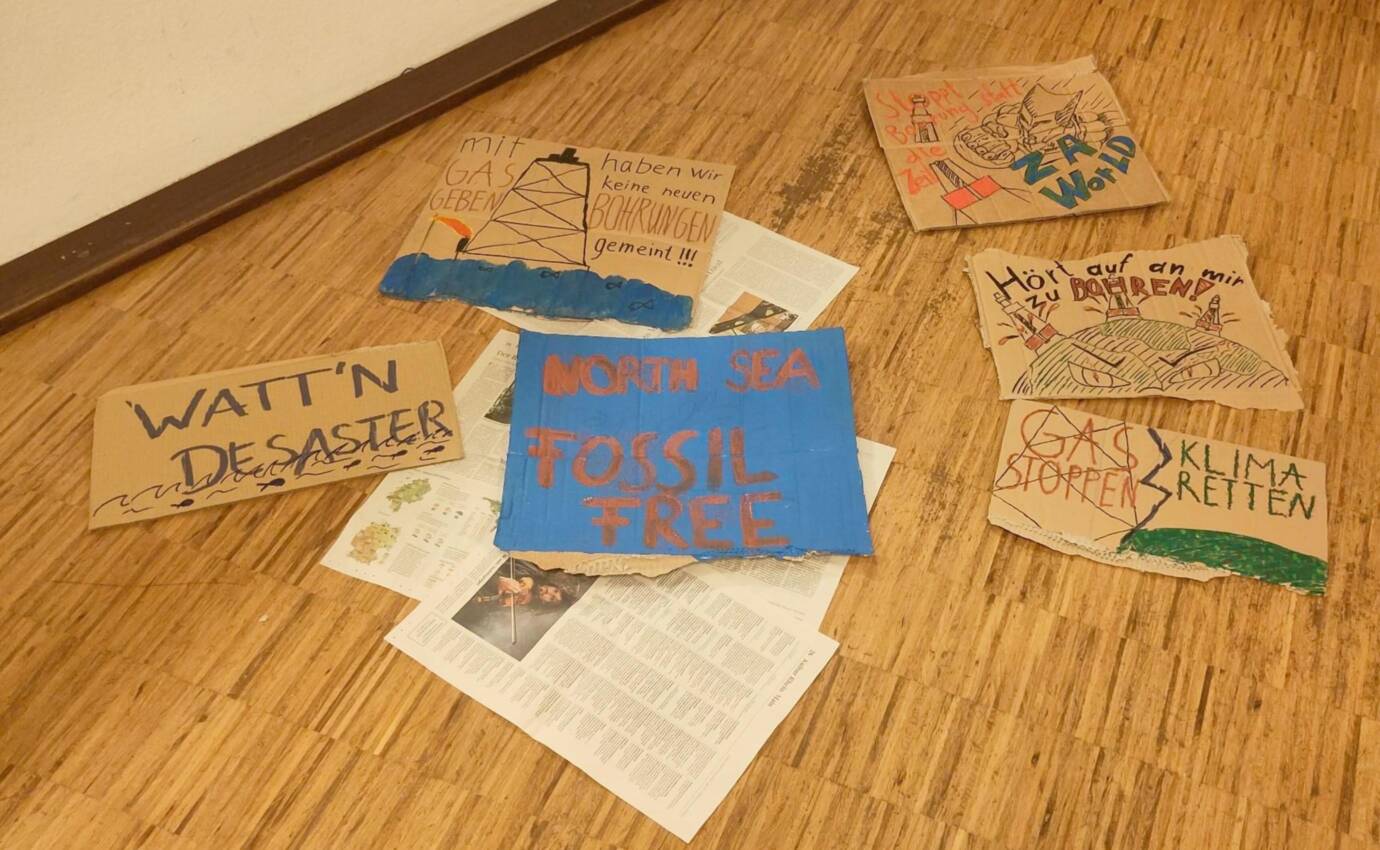 Protestplakate auf Holzboden mit Umweltbotschaften.