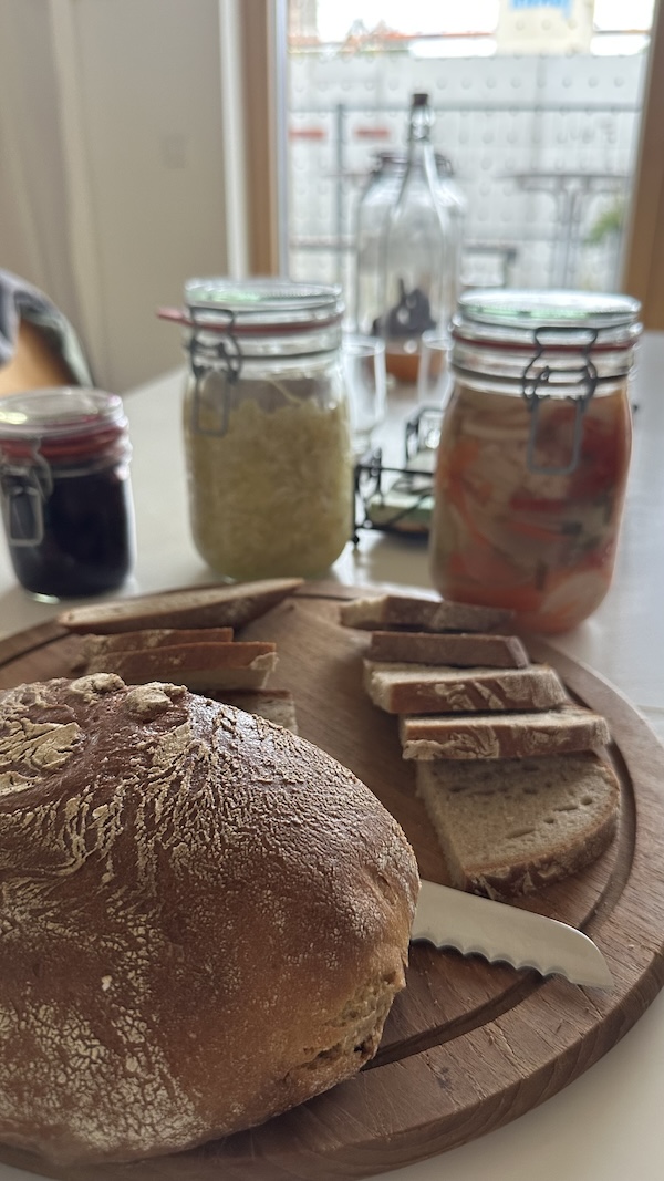 Frisches Brot und Einmachgläser auf Holzteller.