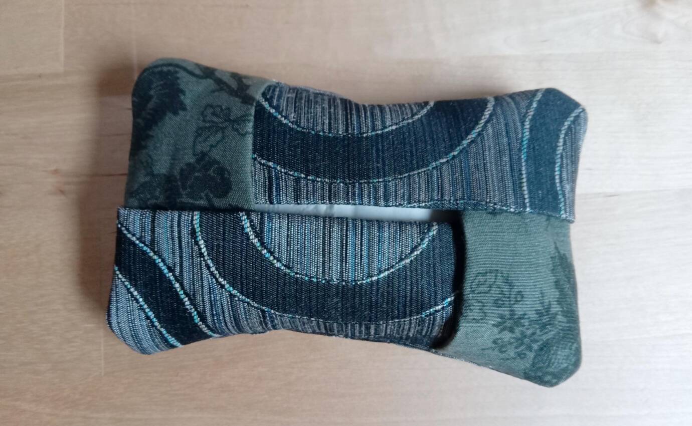 Gestreiftes, gemustertes Stoffkissen auf hellem Hintergrund.