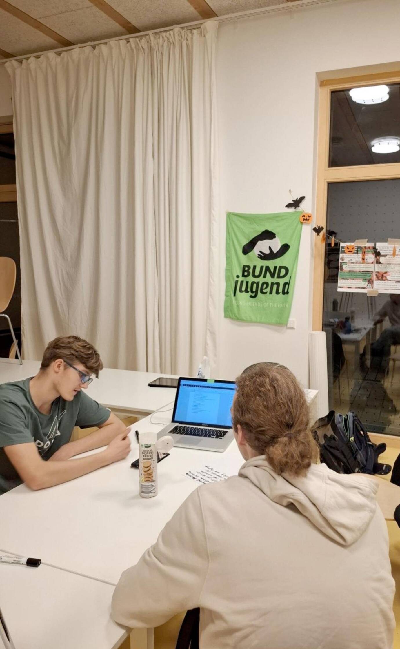 Zwei Personen arbeiten an einem Tisch mit Laptop.