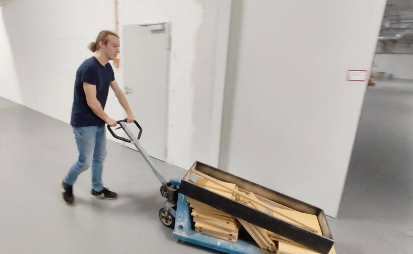 Eine Person schiebt einen Wagen mit Holz.